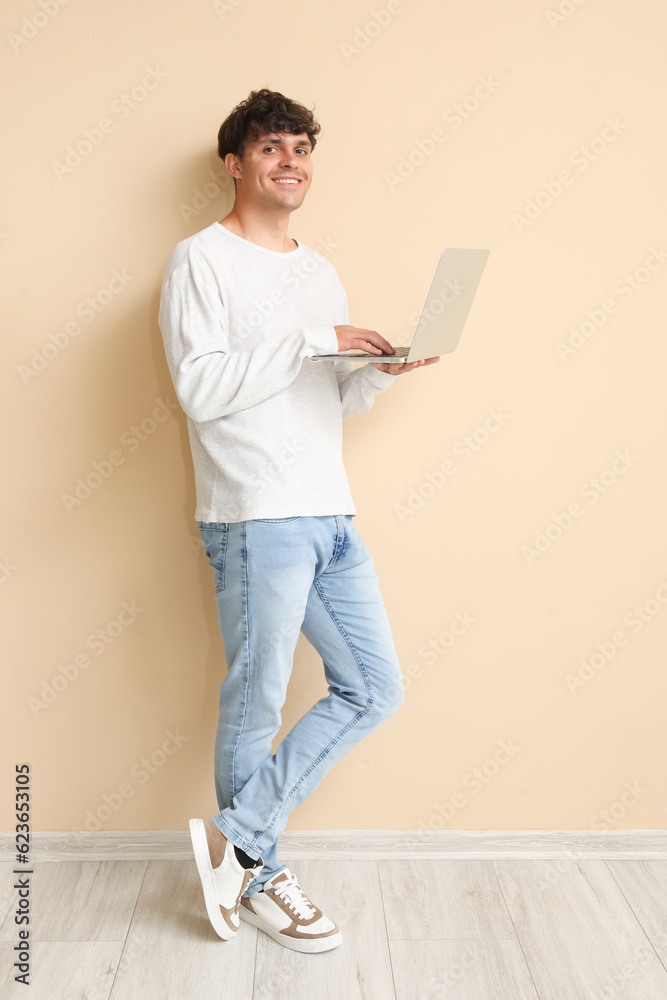 Male programmer working with laptop near beige wall