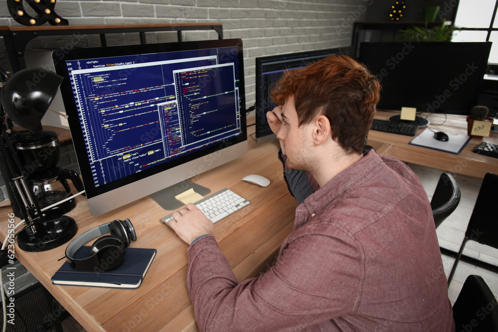 Male programmer working with computer at table in office