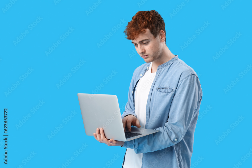 Male programmer working with laptop on blue background