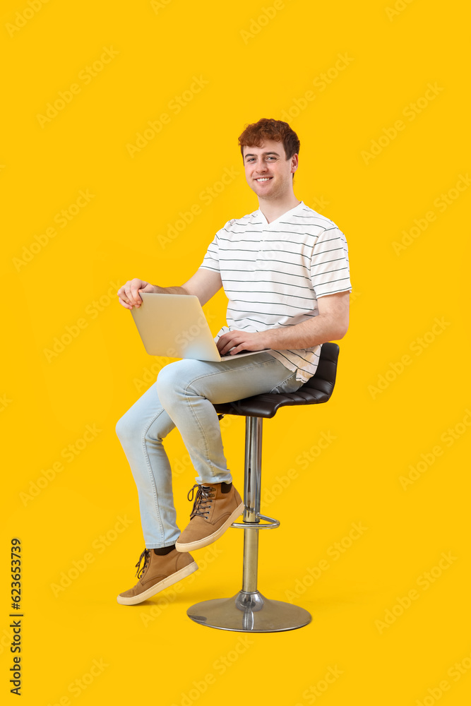 Male programmer working with laptop on yellow background