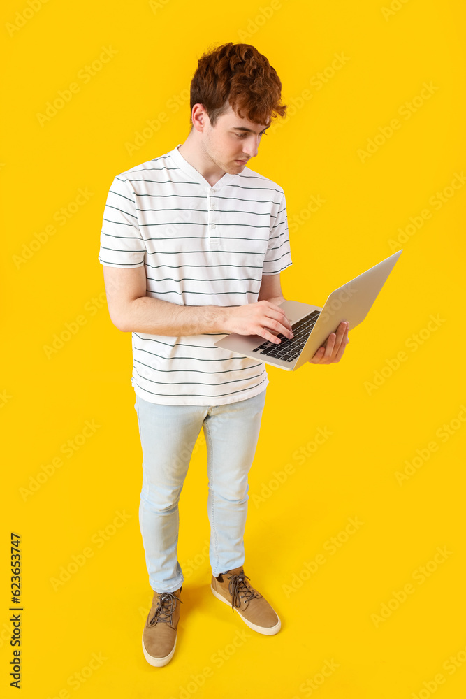 Male programmer working with laptop on yellow background