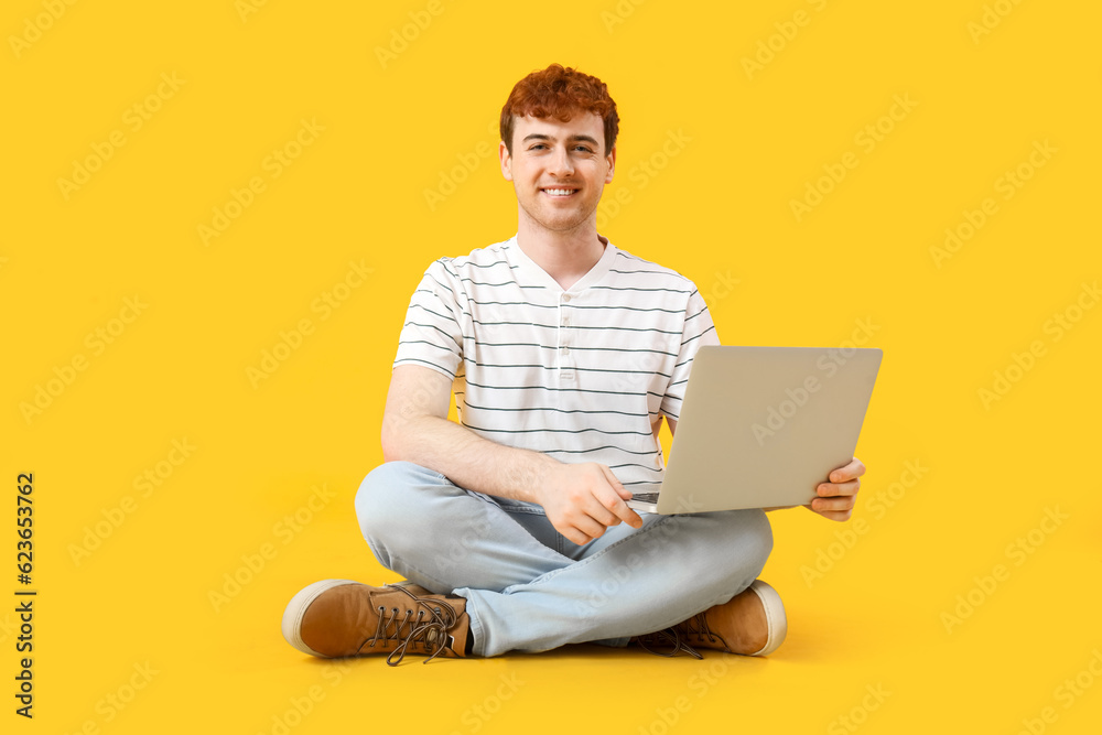 Male programmer working with laptop on yellow background