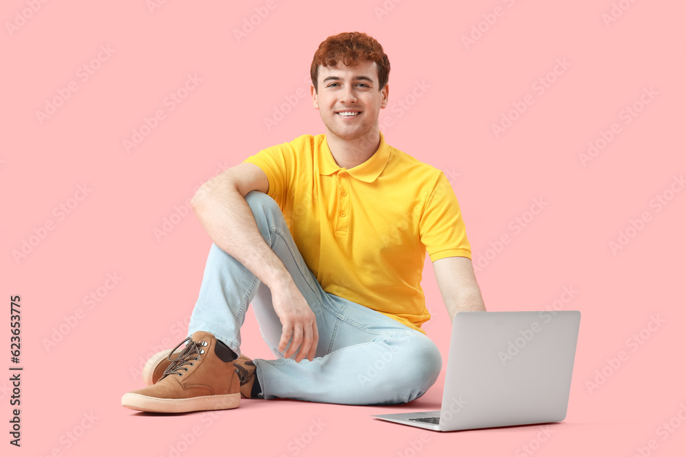 Male programmer working with laptop on pink background