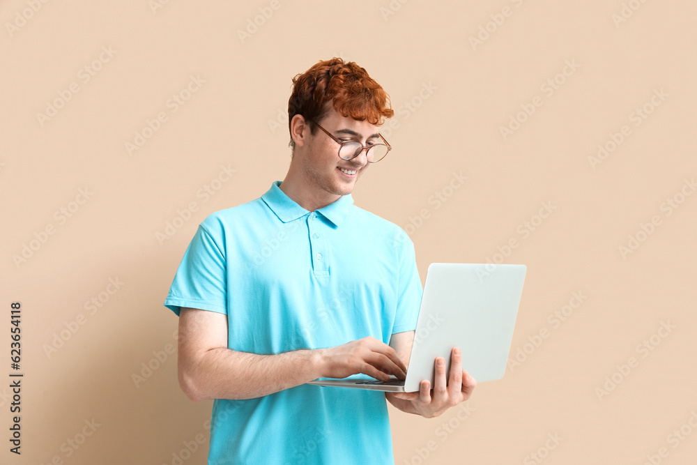 Male programmer working with laptop on beige background