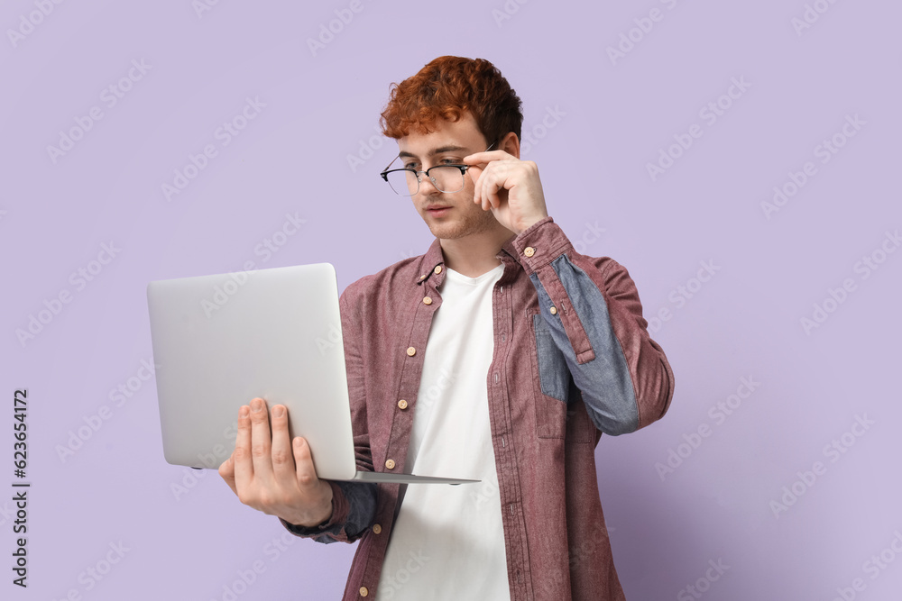 Male programmer working with laptop on lilac background