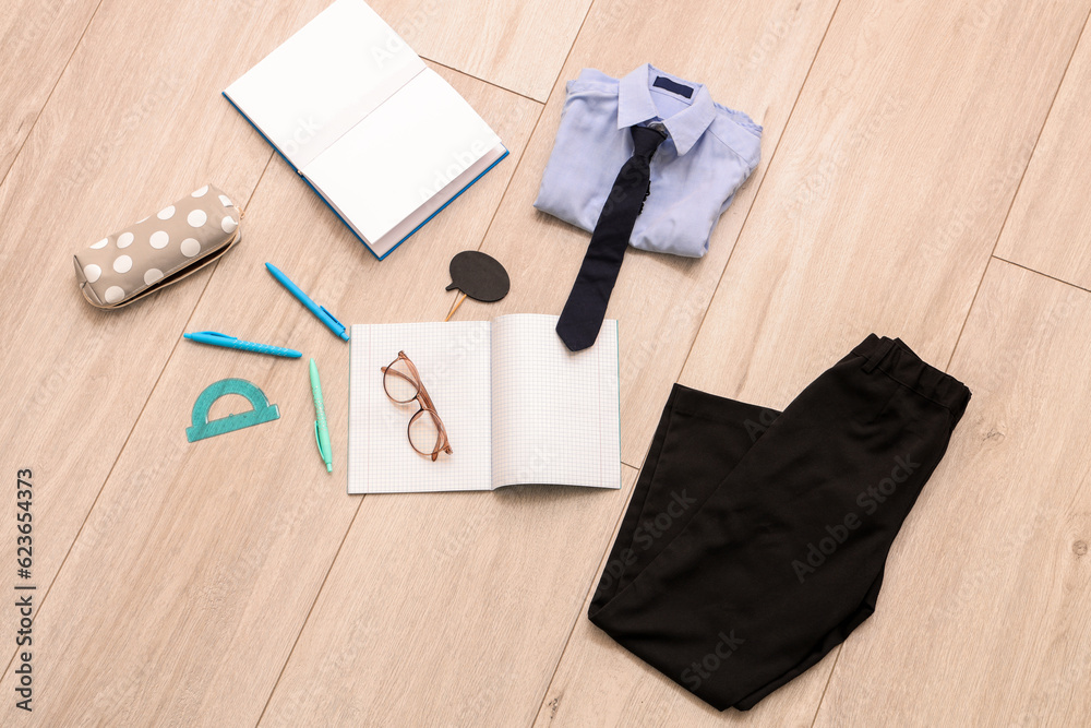 Composition with stylish school uniform, eyeglasses and stationery on wooden background