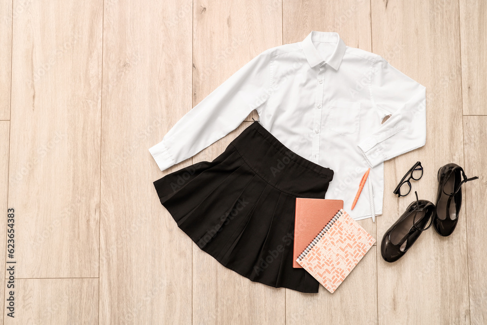 Composition with stylish school uniform, shoes, eyeglasses and stationery on wooden background