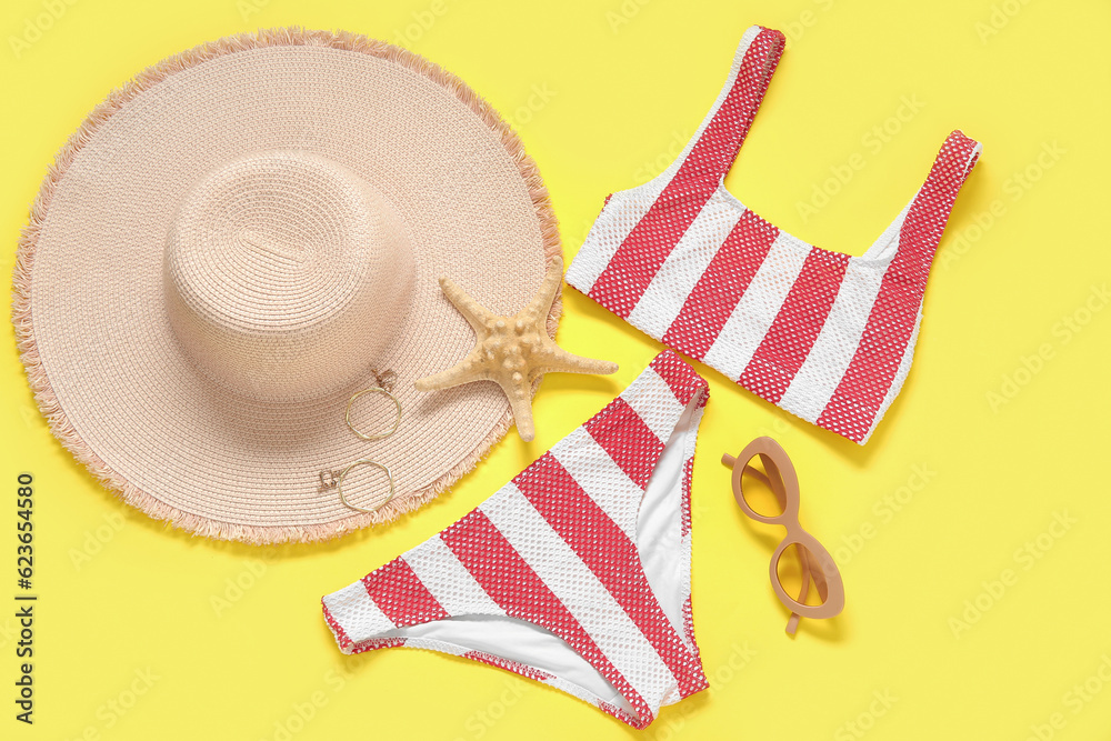 Stylish swimsuit, sunglasses, hat, earrings and starfish on yellow background