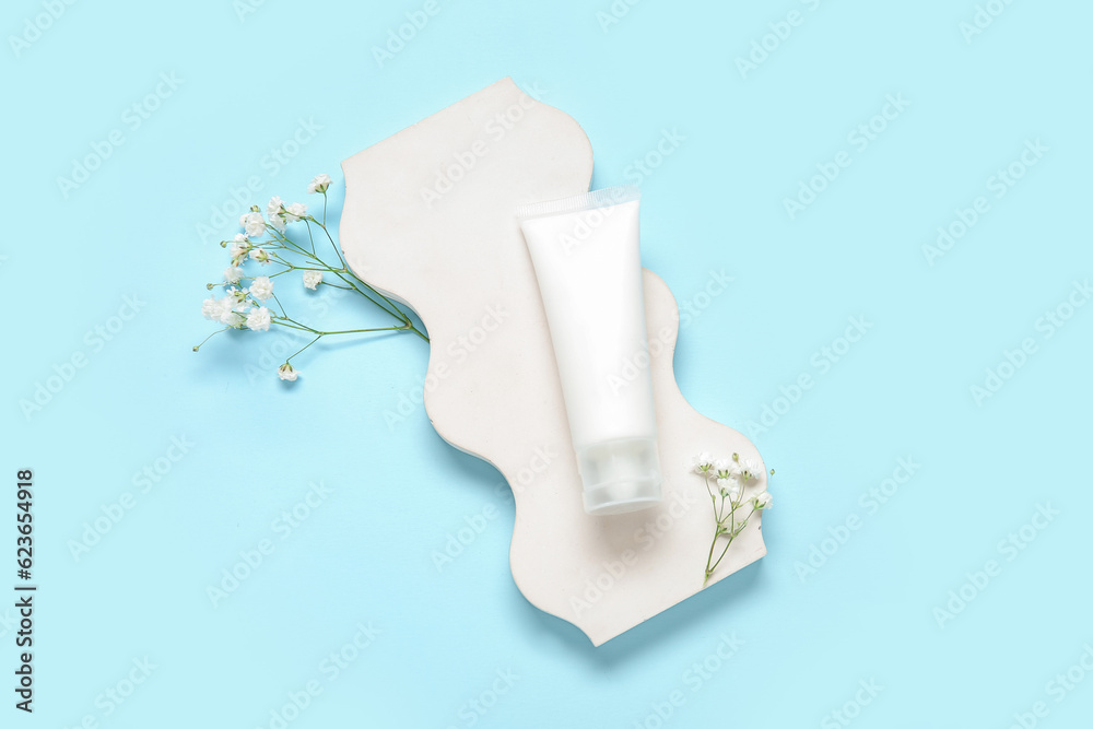 Composition with plaster podium, cosmetic product and gypsophila flowers on color background