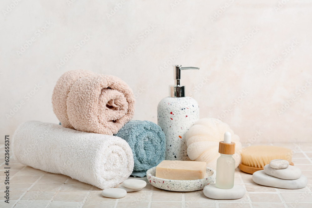 Set of bath supplies with bottle of essential oil on light tile table