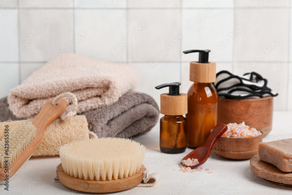 Set of bath supplies with massage brushes on table near light tile wall