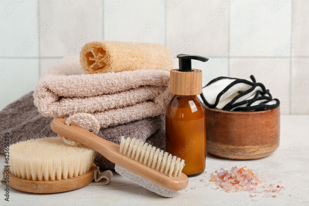 Set of bath supplies with massage brushes on table near light tile wall