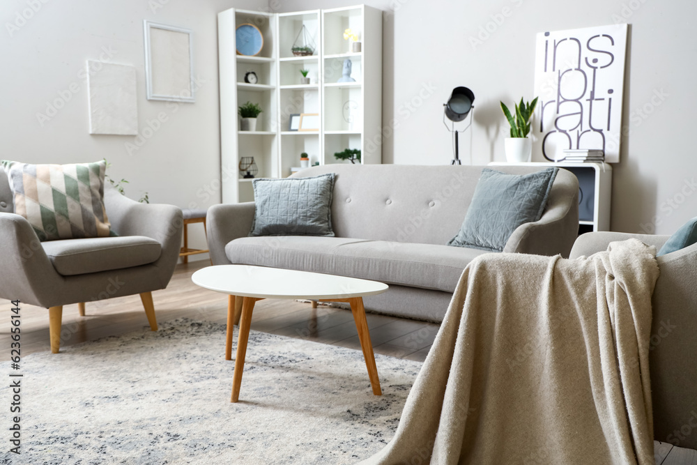 Interior of light living room with sofa, armchairs and coffee table