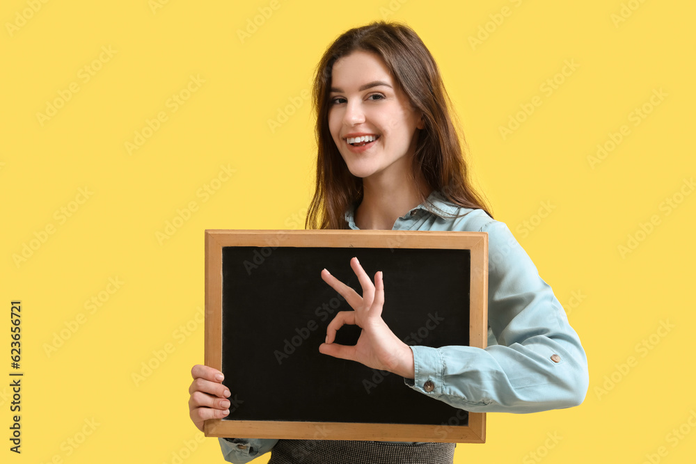 Female teacher with chalkboard showing OK on yellow background