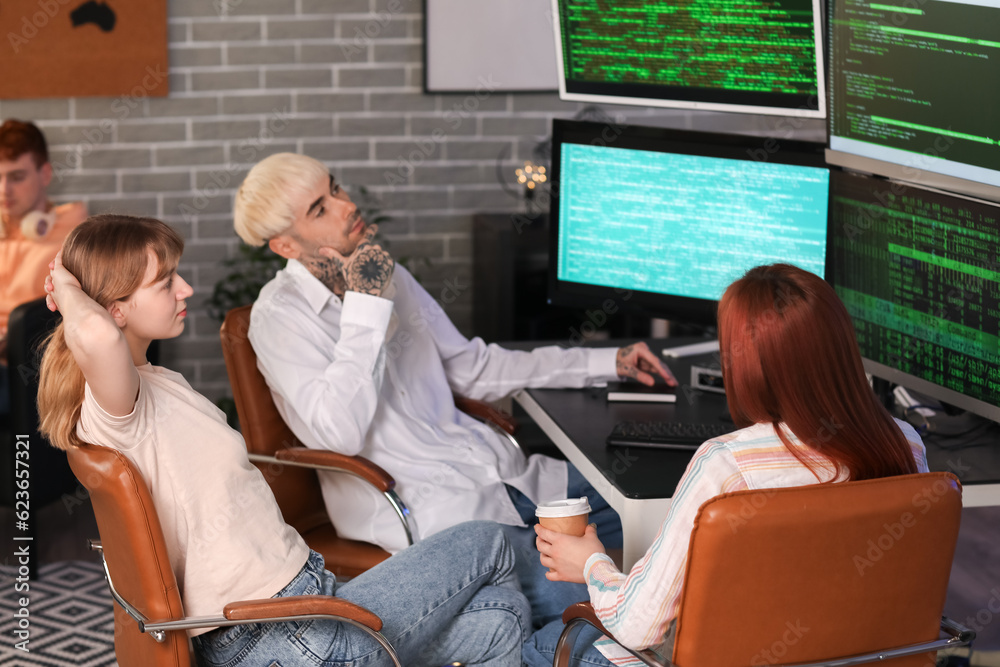 Team of young programmers working in office at night