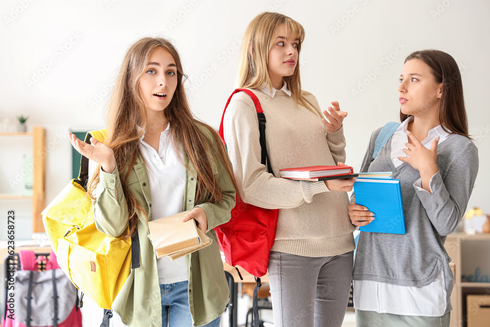 Shocked female students with books in classroom