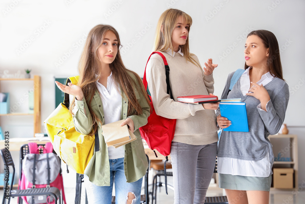 Confused female students with books in classroom