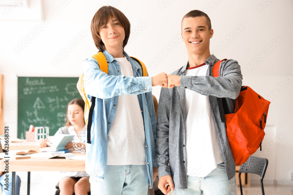 Male students bumping fists in classroom