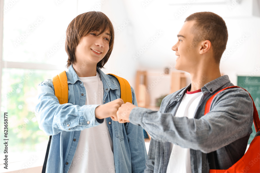 Male students bumping fists in classroom