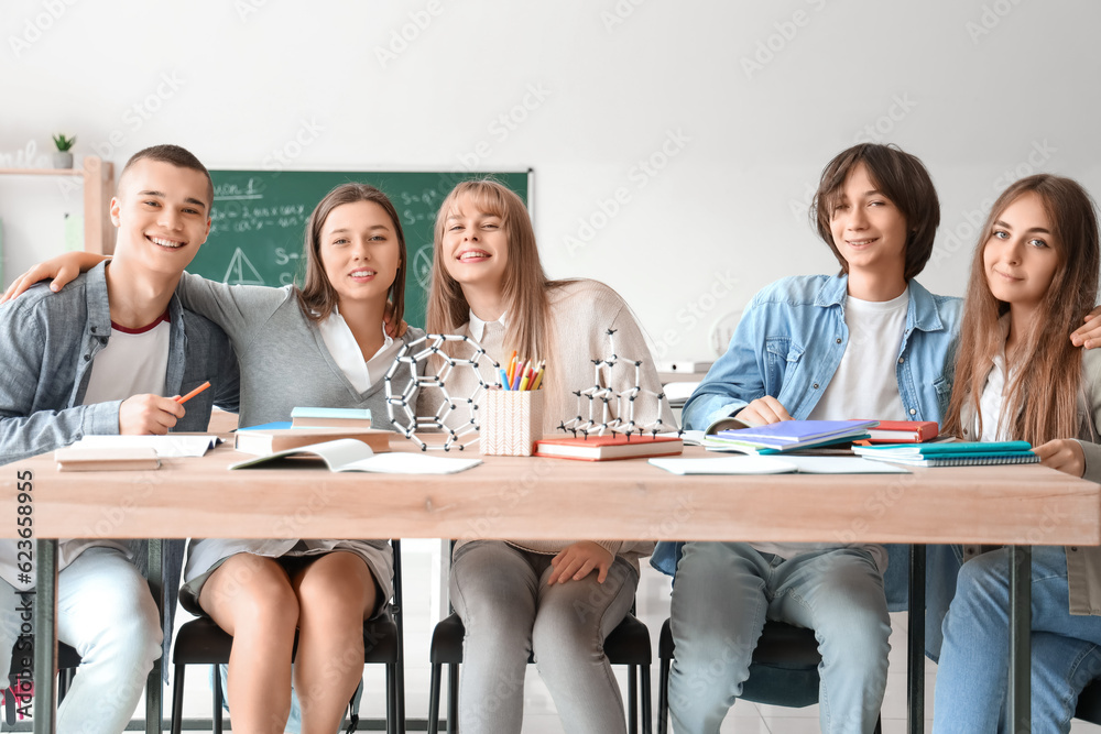 Group of teenage students studying at table in classroom