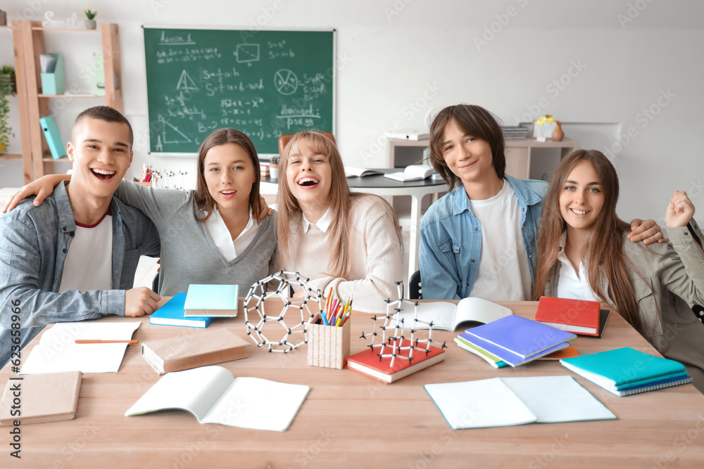 Group of teenage students studying at table in classroom