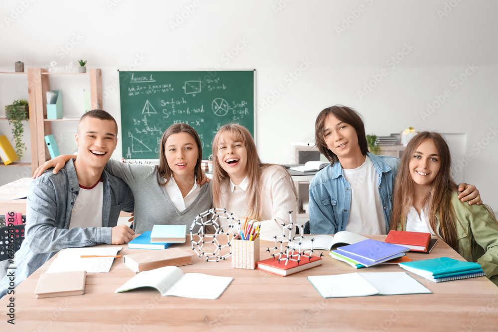 Group of teenage students studying at table in classroom