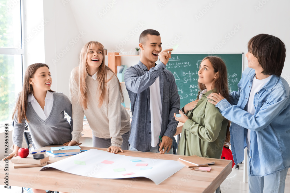 Group of teenage students performing task at table in classroom