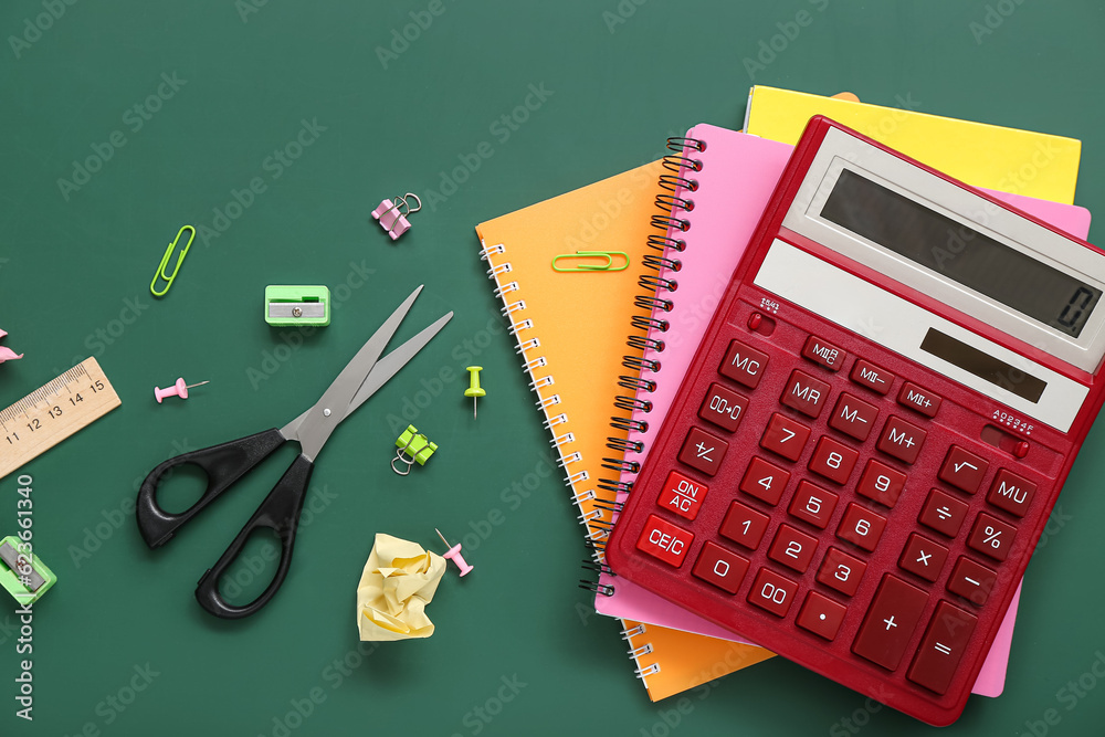 Calculator and different stationery on green chalkboard