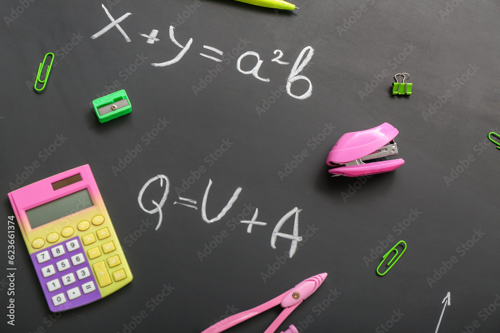 Different stationery on black chalkboard with formulas