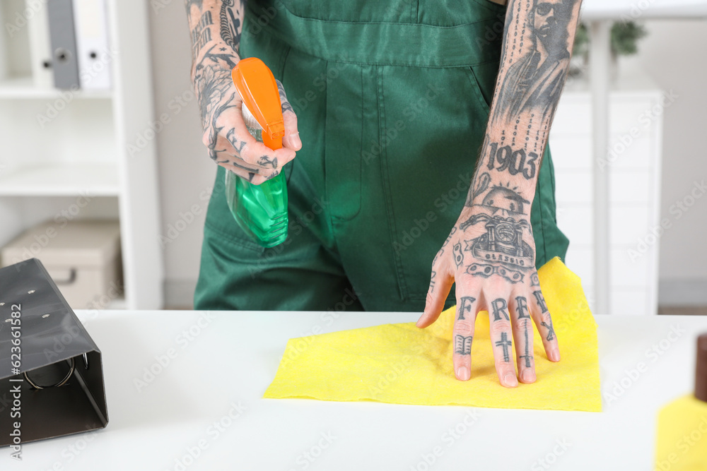 Male janitor cleaning table in room, closeup