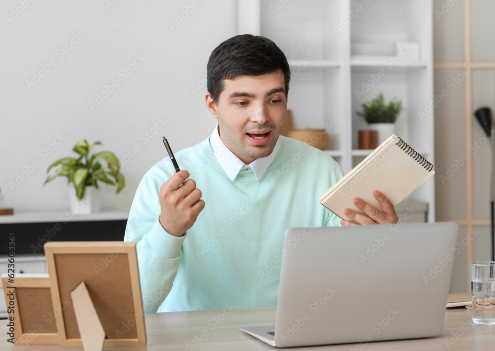 Young man with notebook having job interview online at home