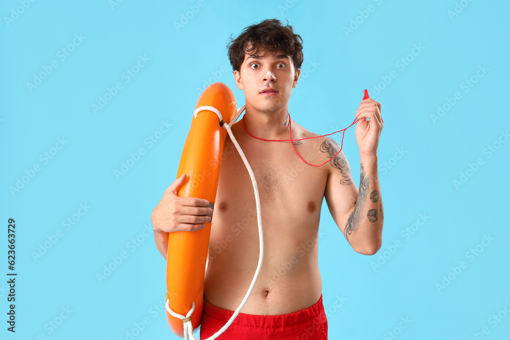 Male lifeguard with whistle and ring buoy on blue background