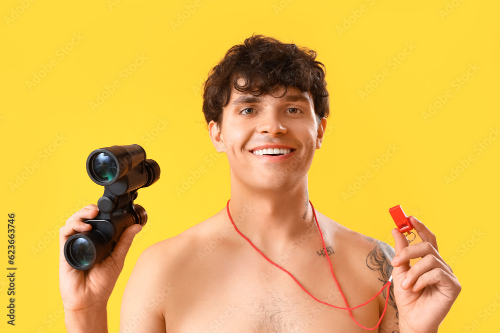 Male lifeguard with binoculars and whistle on yellow background, closeup