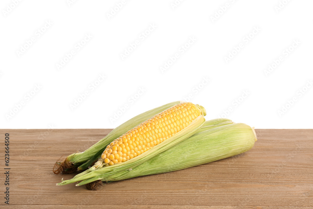 Fresh corn cobs on wooden table against white background