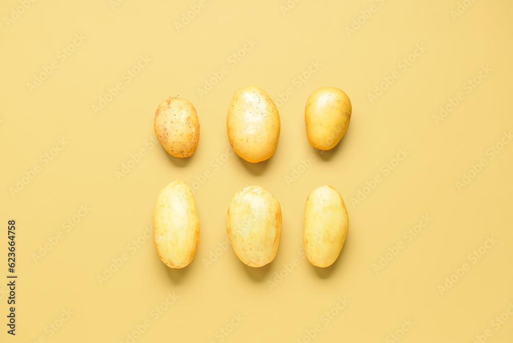 Raw potatoes on yellow background