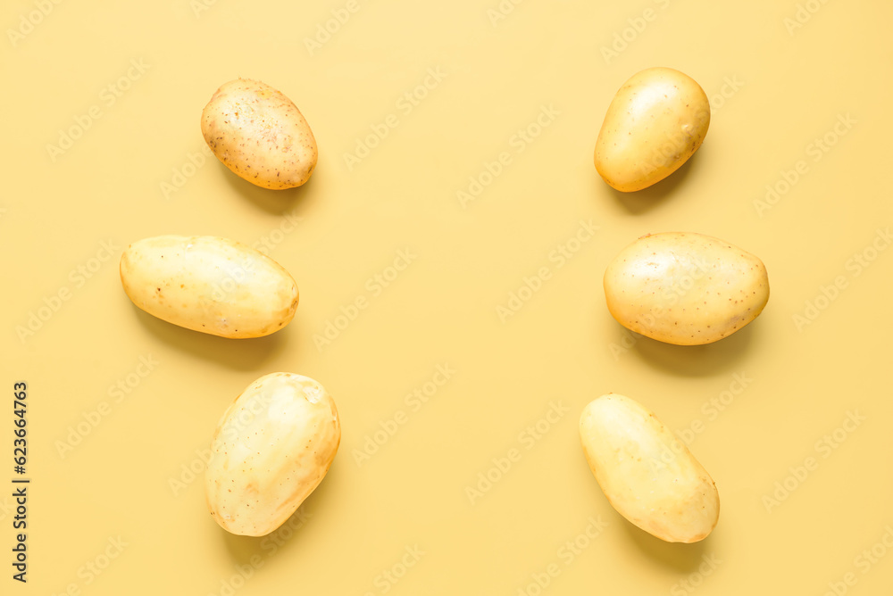 Raw potatoes on yellow background