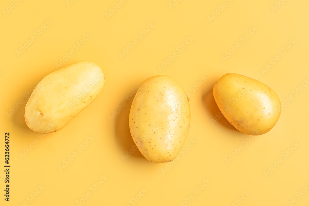 Raw potatoes on yellow background