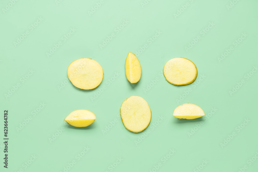 Pieces of raw potato on green background