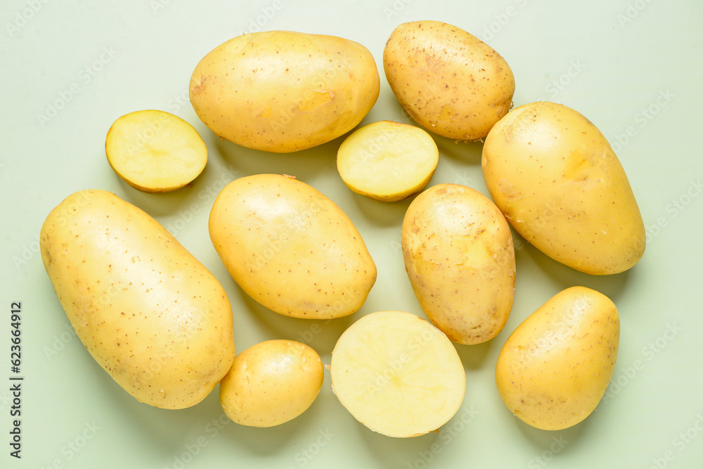 Raw potatoes on green background