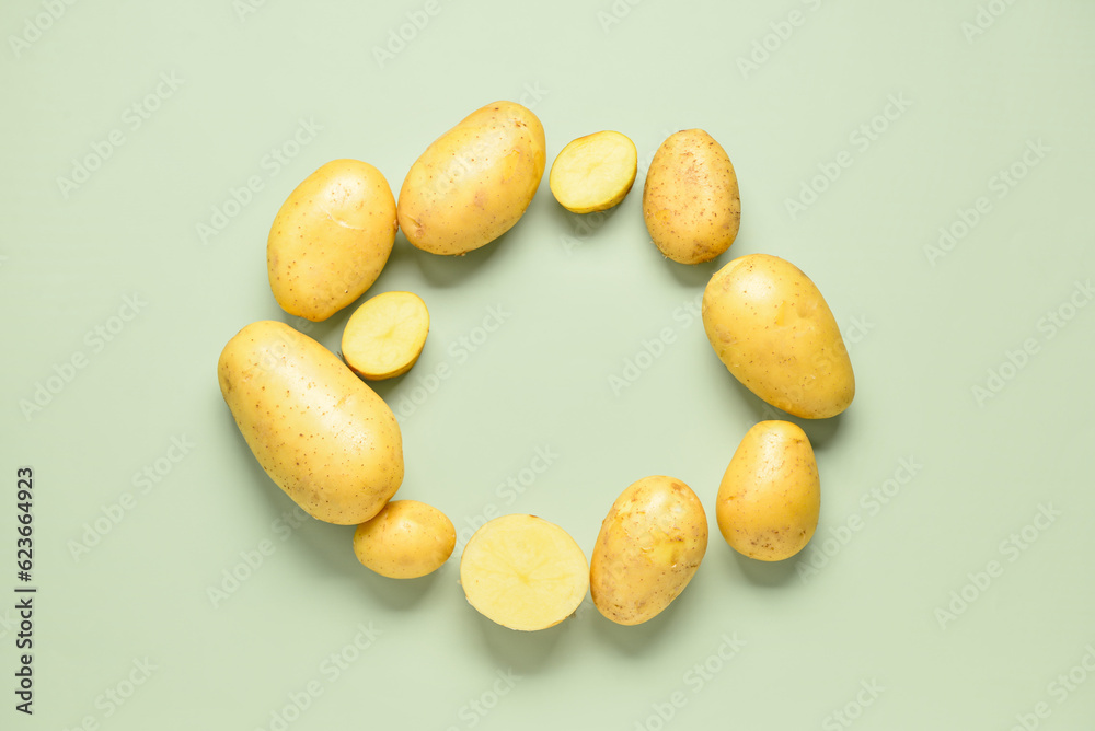 Frame made of raw potatoes on green background