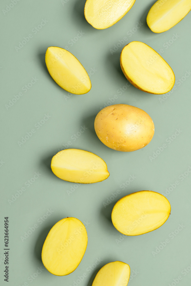 Raw potatoes on green background