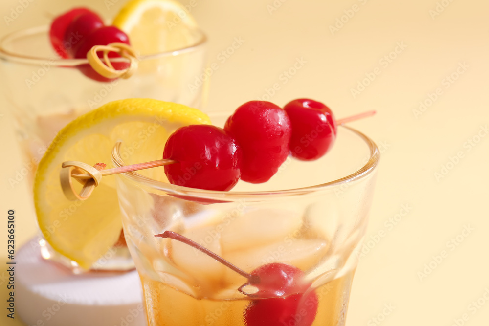 Glasses of tasty cocktail with maraschino cherries on yellow background