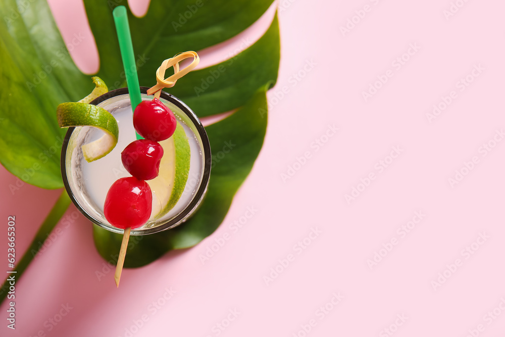 Glass of tasty cocktail with maraschino cherries on pink background