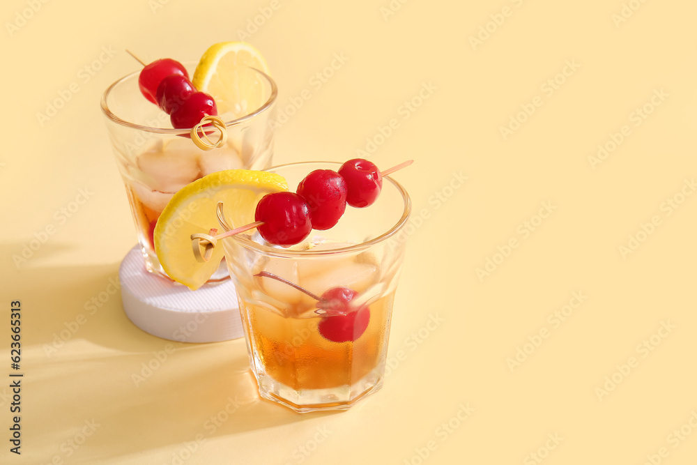 Glasses of tasty cocktail with maraschino cherries on yellow background