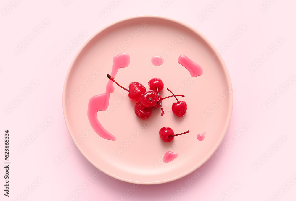 Plate with tasty maraschino cherries on pink background