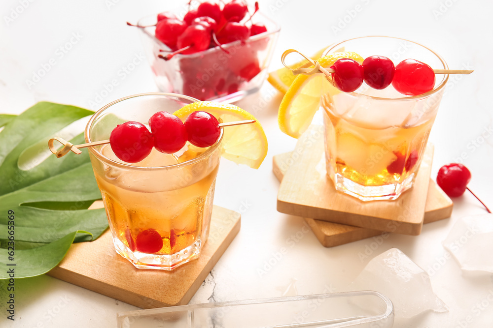 Glasses of tasty cocktail with maraschino cherries on white marble background