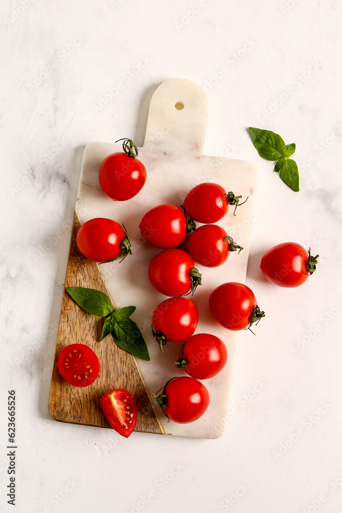 Board with fresh cherry tomatoes and basil on white background