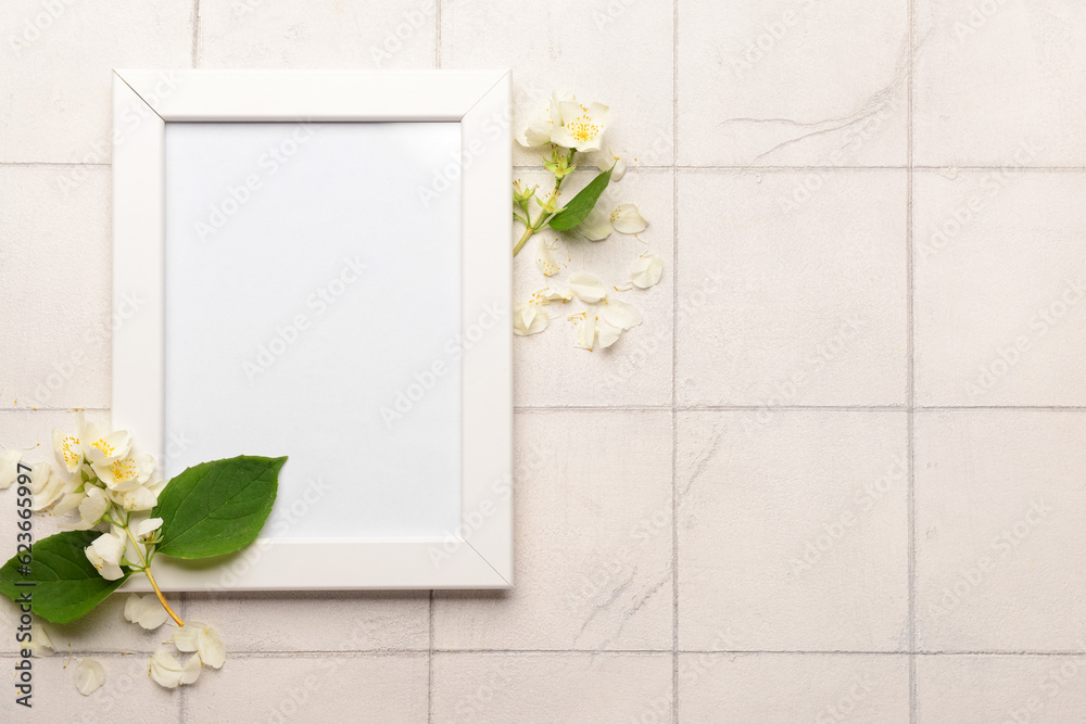 Blank photo frame and beautiful flowers on white tile background