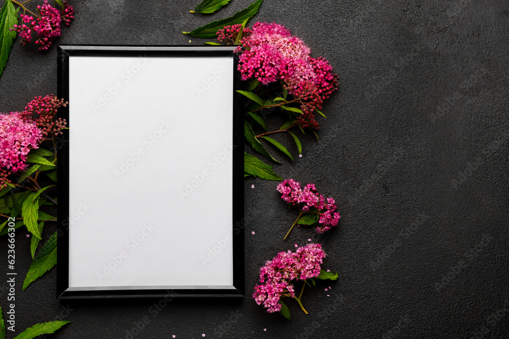 Blank photo frame and beautiful flowers on black background