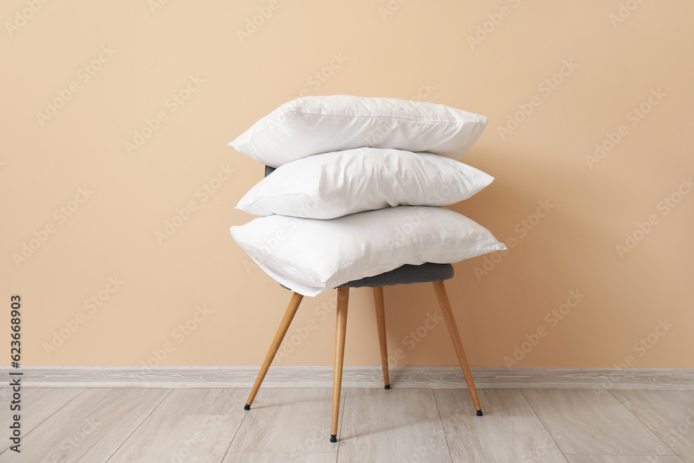 White pillows on chair near beige wall